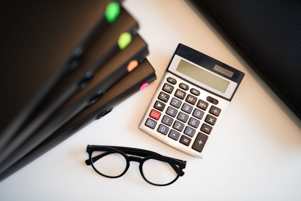 Mastering the First Impression: Your intriguing post title goes here Calculator with glasses and folders on an office desk. Perfect for finance and accounting themes.
