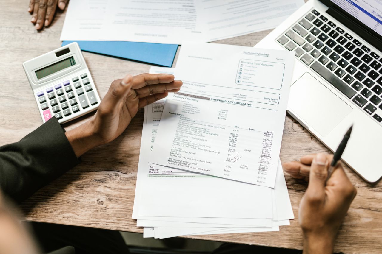 Crafting Captivating Headlines: Your awesome post title goes here Hands holding financial documents with calculator and laptop on office desk, business analysis scene.